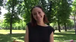 Junge Brünette mit langen Haaren sitzt schüchtern auf sonniger Parkbank unter grünen Bäumen