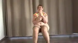 Dicke blonde Frau mit großen Titten zieht ihr Kleid über die schweren Brüste und entblößt ihren runden Bauch.