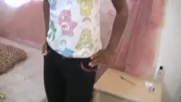 Junge schwarze Frau mit weißem T-Shirt sitzt schüchtern auf einem Bett in einem rosa Zimmer
