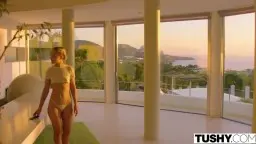 Blondes Model mit Zöpfen und weißem Top steht mit dem Rücken zu einem Mann in weißem Hemd vor Pool und Meer bei Sonnenuntergang