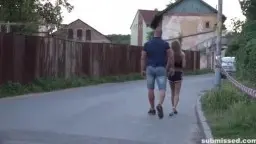 Sarah Kay sitzt gefesselt auf dem Bordstein, während ein kräftiger Mann sie von hinten brutal festhält.