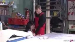 Reife Brünette im weißen Top steht mit Mechaniker in der Werkstatt