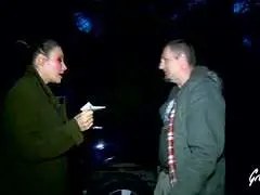 Nahaufnahme einer Frau mit starkem Make-up, geöffnetem Mund und grüner Jacke bei Nacht
