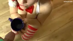 Blonder Weihnachtsengel kniet auf Holzboden und hält blauen Becher für Pisse bereit
