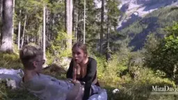 Blonde Frau kniet im Freien und bläst einen Mann vor schneebedeckten Alpen
