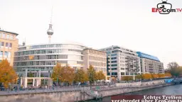 Mollige Brünette mit offenem Mantel und blanken schweren Brüsten posiert selbstbewusst vor Graffiti-Wand in der Stadt