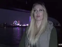 Blonde Frau mit langem Haar hält schwarzen Regenschirm vor Graffiti-Wand