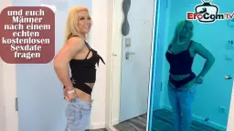 Blonde MILF mit Piercing-Titten posiert verführerisch in schwarzem Top und Jeans im Flur