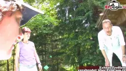 Reife Frau in lila Shirt und roter Kappe steht zwischen jungem Mann mit Basecap und grinsendem Kerl im Freien
