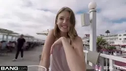 Lachende blonde Teenfotze im rosa Top macht Selfie am sonnigen Balkon mit Pier im Hintergrund