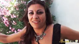 Latina in schwarzem Top lächelt vor blühendem Busch