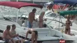 Nacktes Pärchen knutscht wild auf rotem Jetski inmitten von Yachten und Booten im Hafen