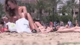 Vollbusige Blondine liegt oben ohne am sonnigen Sandstrand und präsentiert ihre riesigen nackten Brüste