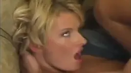 Leidenschaftlicher Kuss zwischen großer Blondine und Mann im Wohnzimmer, er umfasst ihre nackten Brüste